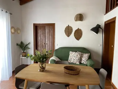 a living room with a table and a green couch at Casa Alfarroba in Barão de São Miguel