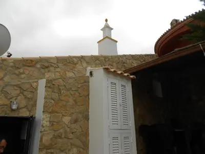 a white door on the side of a stone wall with a cross at Casa Alfarroba in Barão de São Miguel
