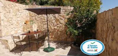 a table with an umbrella next to a stone wall at Casa Alfarroba in Barão de São Miguel