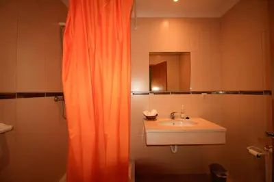 a bathroom with an orange shower curtain and a sink at Paradise Ocean View by AnaLodges in Porto Moniz