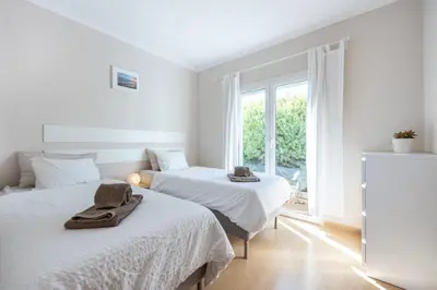 two beds in a white room with a window at Your Villa Algarve Private pool 5 min walk to beach in Burgau
