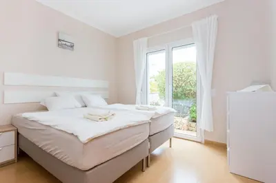 a white bedroom with a large bed and a window at Your Villa Algarve Private pool 5 min walk to beach in Burgau