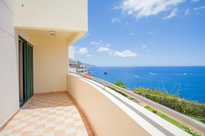 a balcony with two chairs and an umbrella at OurMadeira - 6001 in Funchal