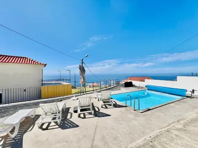 a patio with chairs and a swimming pool at Maria Cottage with Sea View in Estreito da Calheta