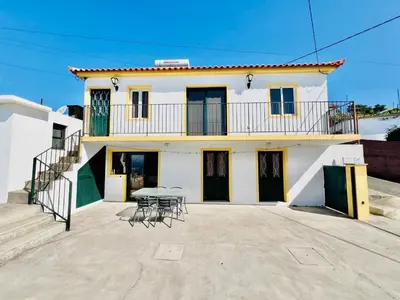 a house with a table and chairs in front of it at Maria Cottage with Sea View in Estreito da Calheta