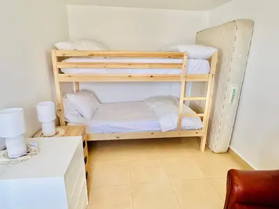 two bunk beds in a room with a desk at Maria Cottage with Sea View in Estreito da Calheta