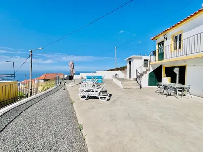 a group of tables and chairs next to a building at Maria Cottage with Sea View in Estreito da Calheta