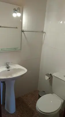 a white bathroom with a toilet and a sink at Ape Esquerdo in São Vicente