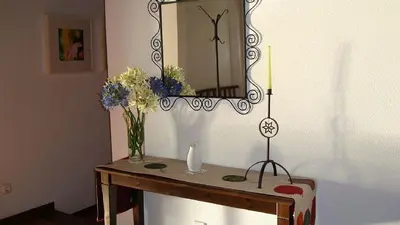 a table with a mirror and a vase of flowers on it at Apartamento Charmoso no Funchal, com grande Jardim e Vista Esplêndida in Funchal