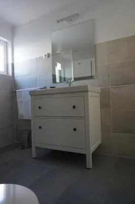 a bathroom with a white dresser with a mirror at Trivial Pisão - Casa de Férias, para a sua Família in Raposeira
