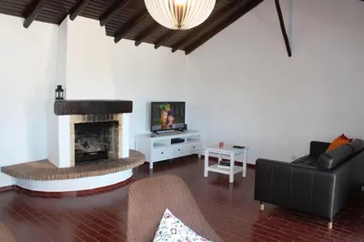 a living room with a couch and a fireplace at Trivial Pisão - Casa de Férias, para a sua Família in Raposeira