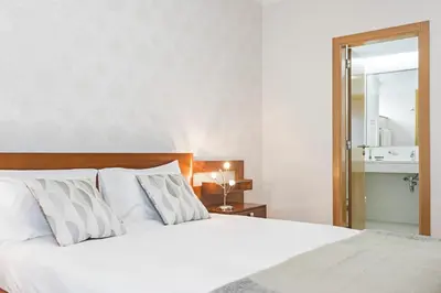 a bedroom with a large white bed and a mirror at Jasmineiro III by An Island Apart in Funchal