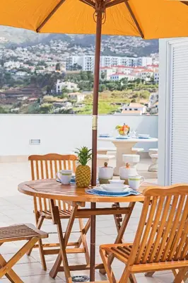 a wooden table with two chairs and an umbrella at Jasmineiro III by An Island Apart in Funchal
