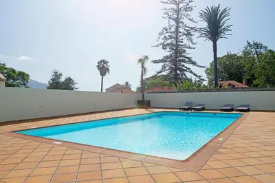 a swimming pool with two chairs and a wall at Jasmineiro III by An Island Apart in Funchal