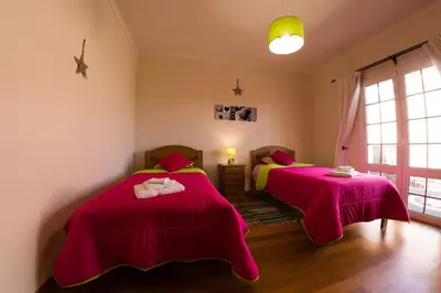 two beds in a room with pink sheets at Casa Nunes in Santana