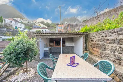 a patio with a table and chairs and a wall at Gouveia Cottage in Seixal