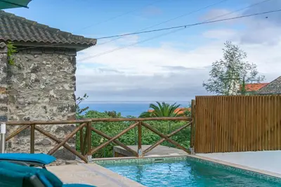 a swimming pool with a wooden fence and the ocean at Gouveia Cottage in Seixal