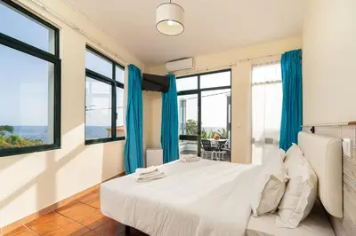 a bedroom with a bed and large windows at TarmarPlace in Jardim do Mar