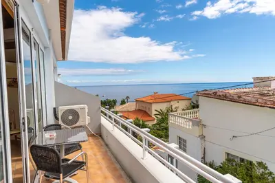 a balcony with a table and chairs looking out at the ocean at TarmarPlace in Jardim do Mar