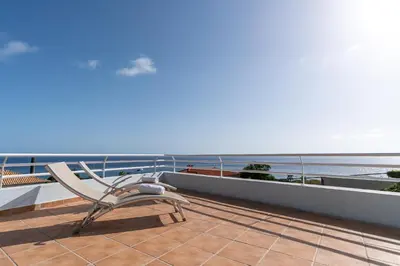 a chair sitting on a balcony looking at the ocean at TarmarPlace in Jardim do Mar