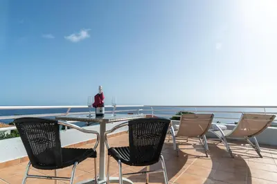 a table and chairs on a balcony with a view of the ocean at TarmarPlace in Jardim do Mar
