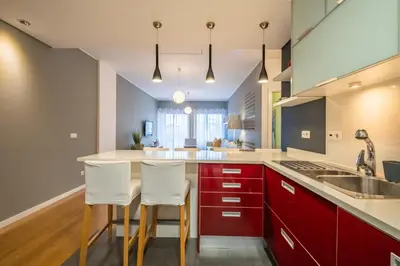 a kitchen with red cabinets and white bar stools at Green Apartment in Funchal