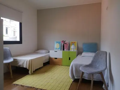 a bedroom with two beds and two chairs and a window at Green Apartment in Funchal