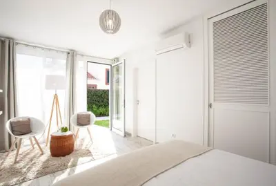 a white bedroom with a bed and two chairs at Quinta B. in Funchal