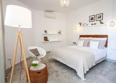 a white bedroom with a bed and a floor lamp at Quinta B. in Funchal