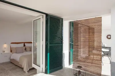 a bedroom with a bed and a glass door with a shower at Quinta B. in Funchal