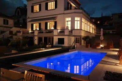 a house with a blue pool in front of a house at Quinta B. in Funchal