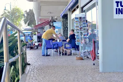 two people sitting at a table outside of a store at Apartamento Romantico in Caniço