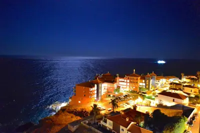 a hotel on the shore of the ocean at night at Apartamento Romantico in Caniço
