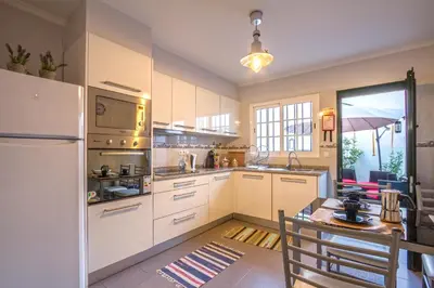 a kitchen with white cabinets and a table and a refrigerator at Old Town House Madeira in Funchal