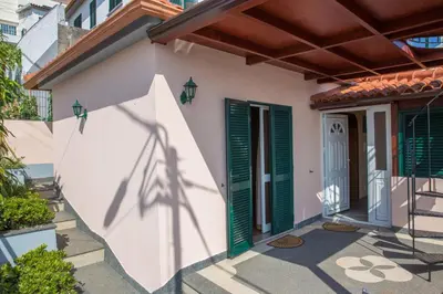 a house with green shutters and a door at Rochinha House in Funchal