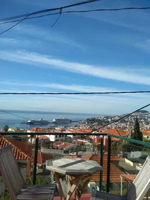 a table and chairs on a balcony with a view of the ocean at Rochinha House in Funchal