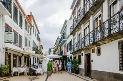a city street with tables and umbrellas on a balcony at Artist Loft - Modern Stay in Historic Old Town in Funchal