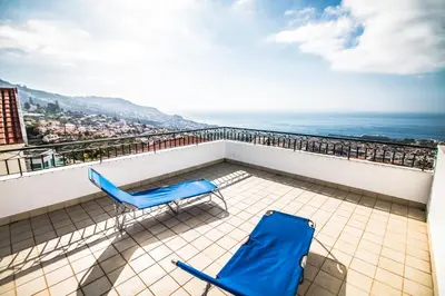 a balcony with two blue chairs and the ocean at Monte Vista Hermosa in Funchal