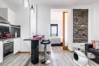 a kitchen and living room with a table and a couch at Enxurros House in Ponta Delgada