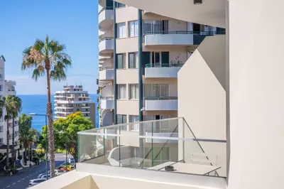 a building with a glass balcony with a view of the ocean at Vila Baleira Residence in Funchal