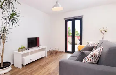 a living room with a gray couch and a tv at Endless Blue House in Arco da Calheta