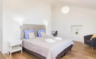 a bedroom with a bed with blue pillows and a chair at Endless Blue House in Arco da Calheta