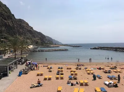 a beach with chairs and people on the beach at Endless Blue House in Arco da Calheta