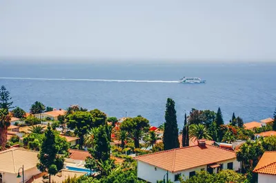 a boat in the water with houses and trees at Horizon View Madeira in Caniço