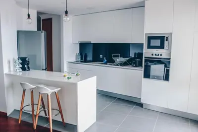 a kitchen with white cabinets and a counter with stools at Horizon View Madeira in Caniço