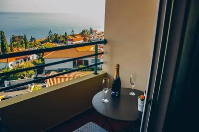 a balcony with a table and two wine glasses at Horizon View Madeira in Caniço