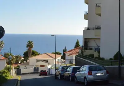 a row of cars parked on a street next to a building at Horizon View Madeira in Caniço