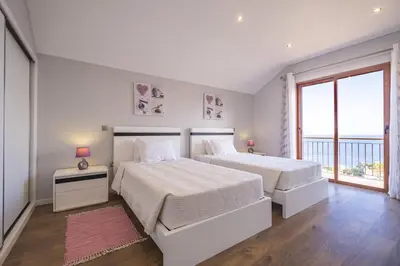 a white bedroom with two beds and a window at Vivenda da Natureza in Santa Cruz
