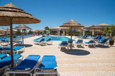 a pool with blue lounge chairs and umbrellas at Boavista Fairviews Village in Lagos