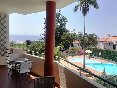 a balcony with a view of the pool and the ocean at Apartment Bay Historic Center in Funchal